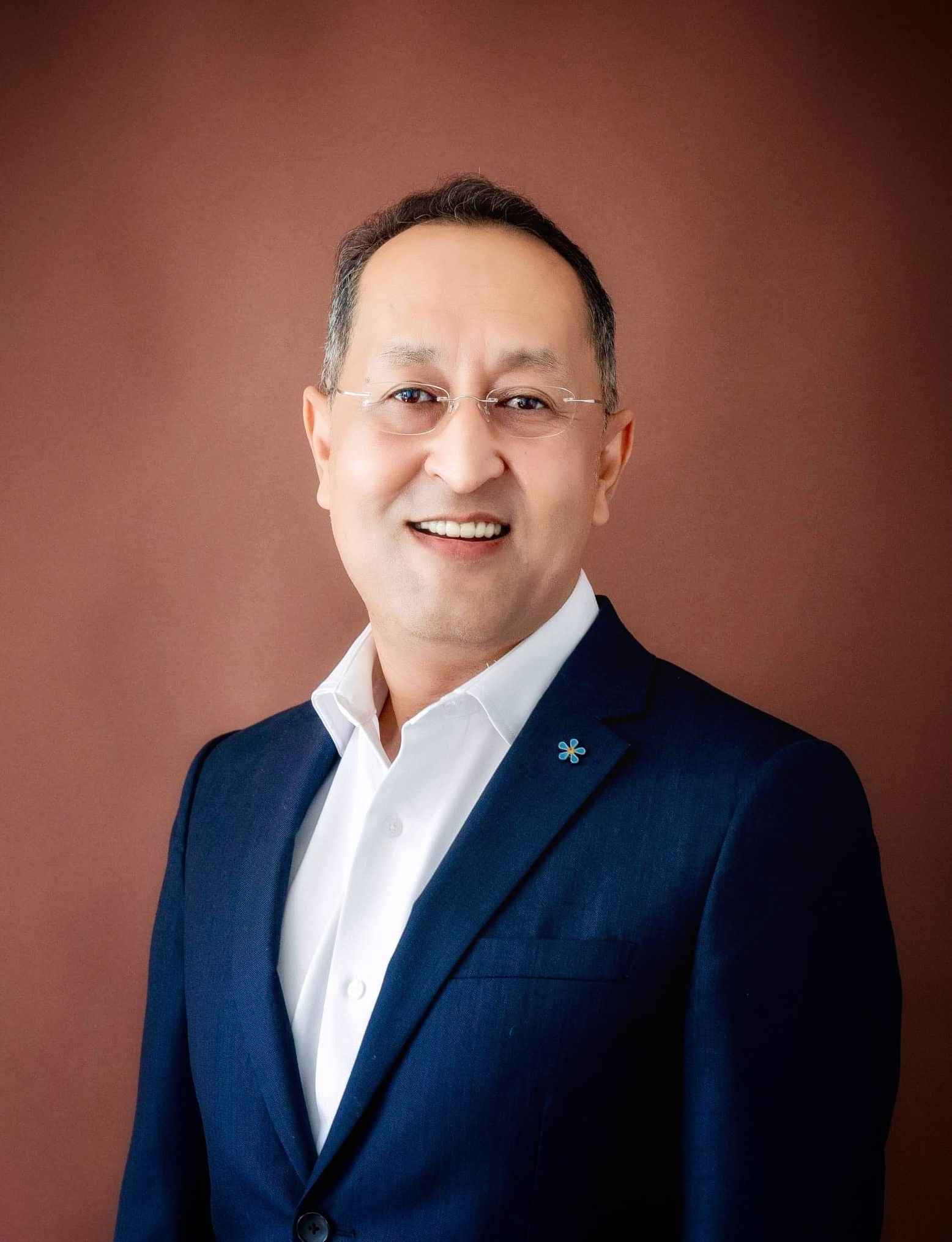 A man in a suit and white shirt is smiling for the camera.