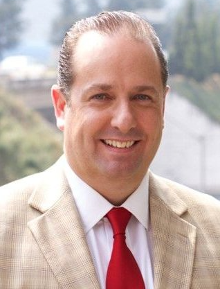 A man in a suit and tie is smiling for the camera