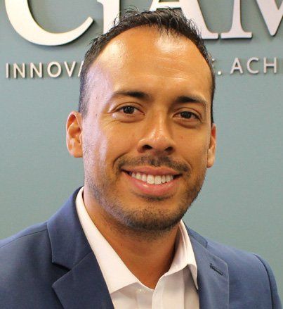 A man in a suit and white shirt is smiling in front of a sign that says innova ach