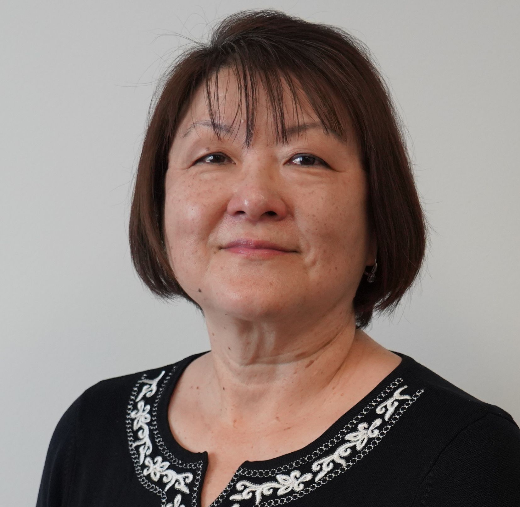 A woman wearing a black shirt with white embroidery on the collar