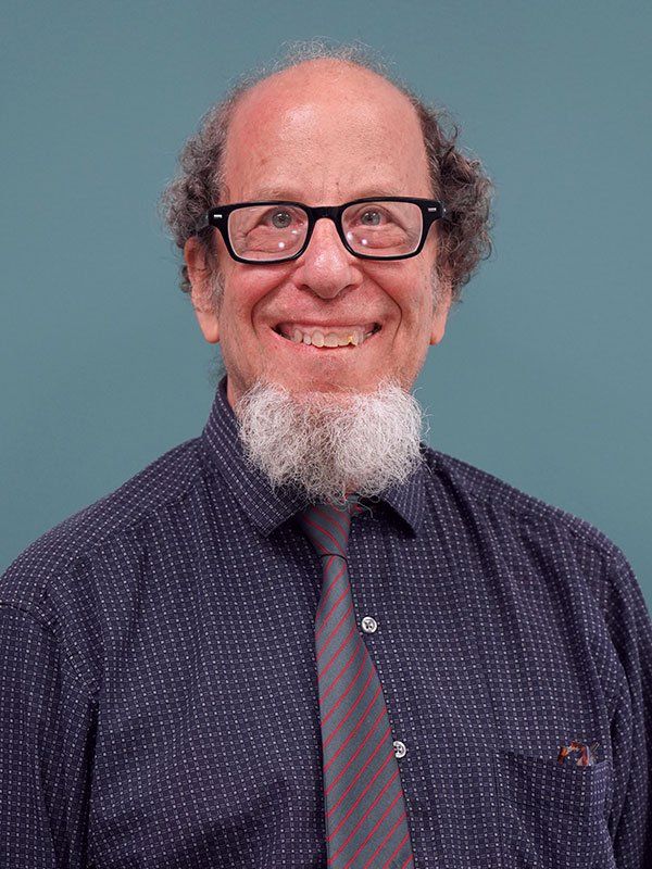 A man with glasses and a beard is smiling for the camera.