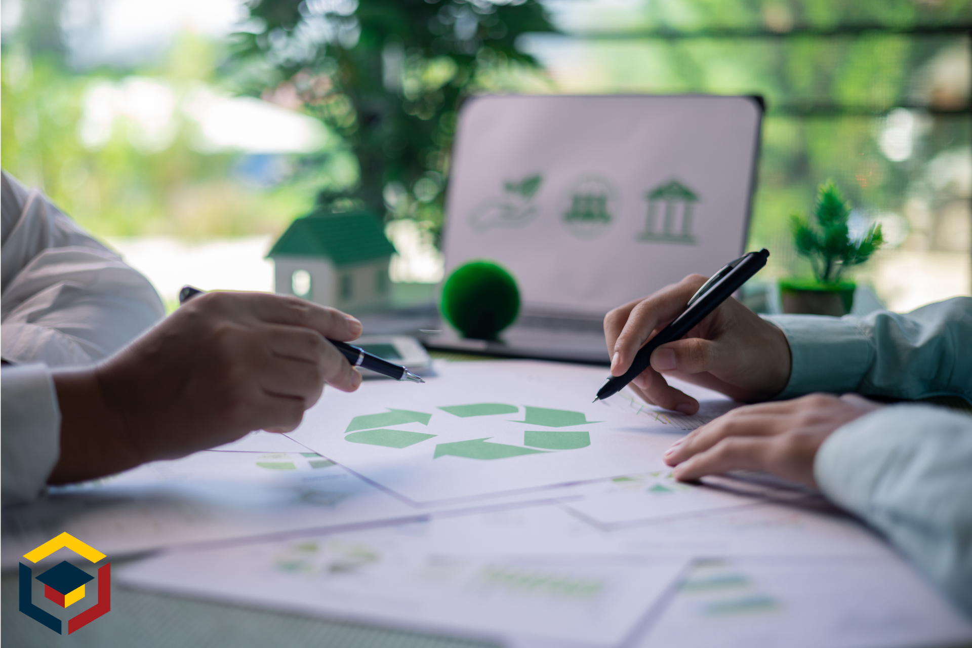 Two people are sitting at a table looking at a recycling symbol on a piece of paper.