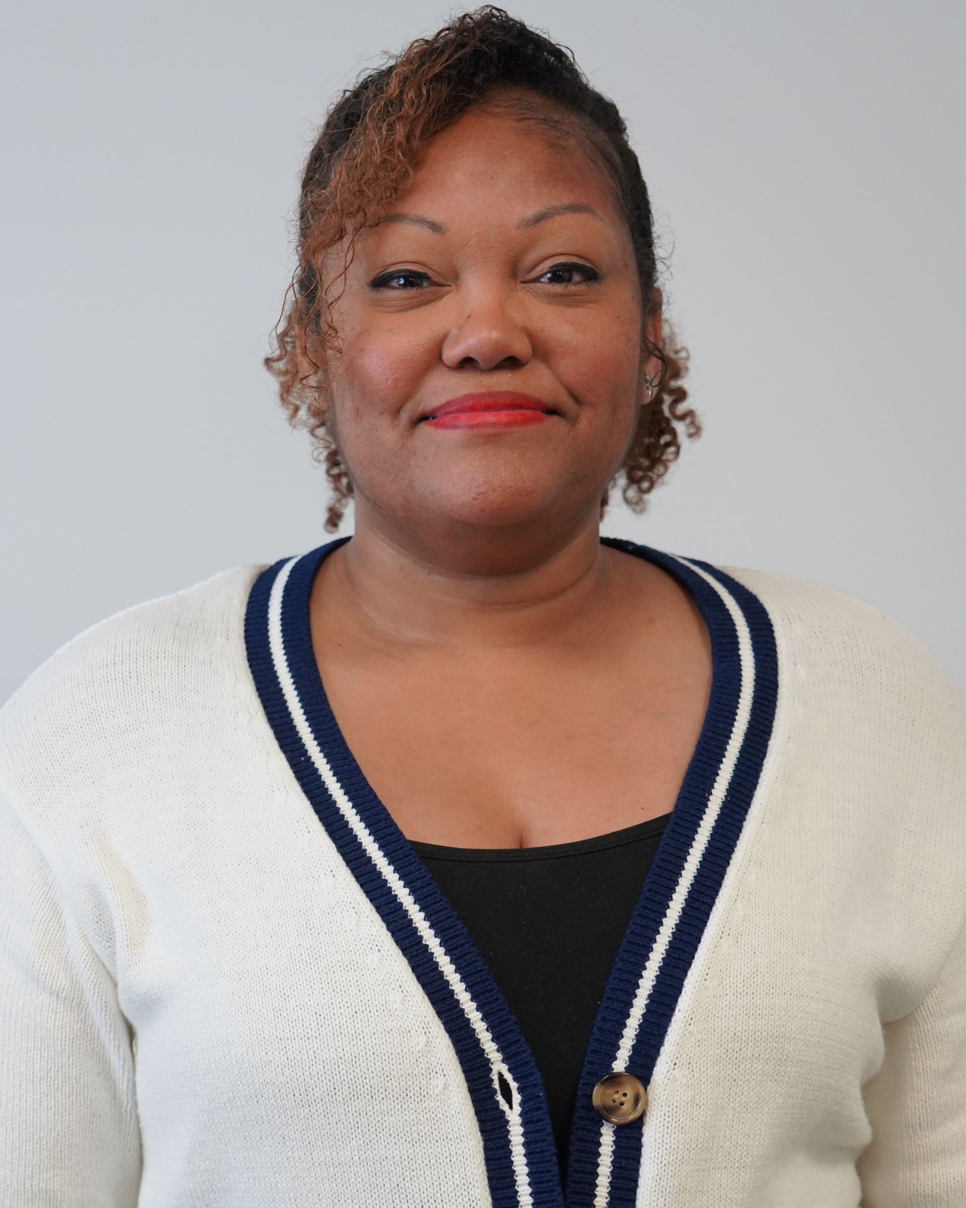 A woman wearing a white and blue sweater smiles for the camera