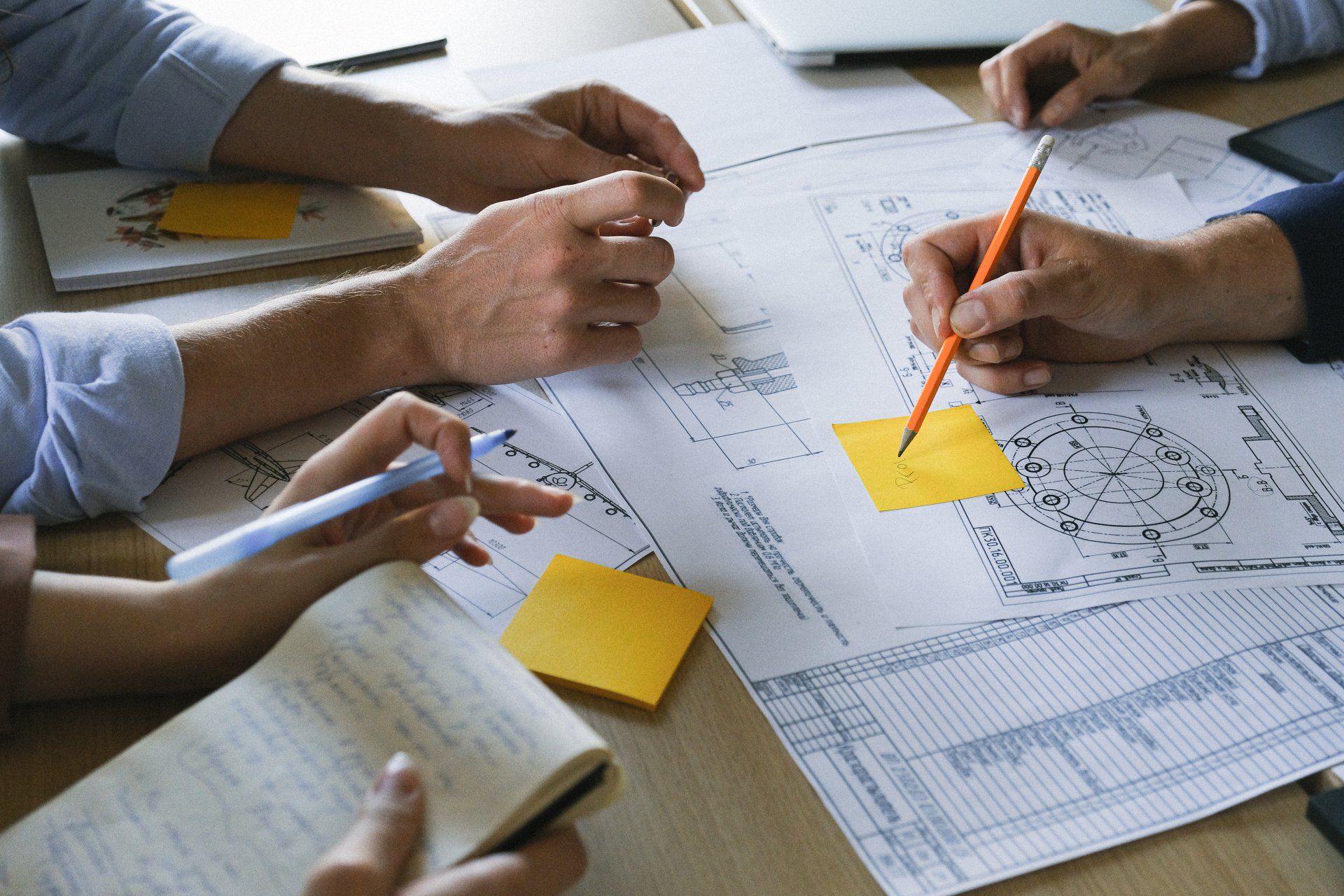 A group of people are sitting at a table looking at a blueprint.