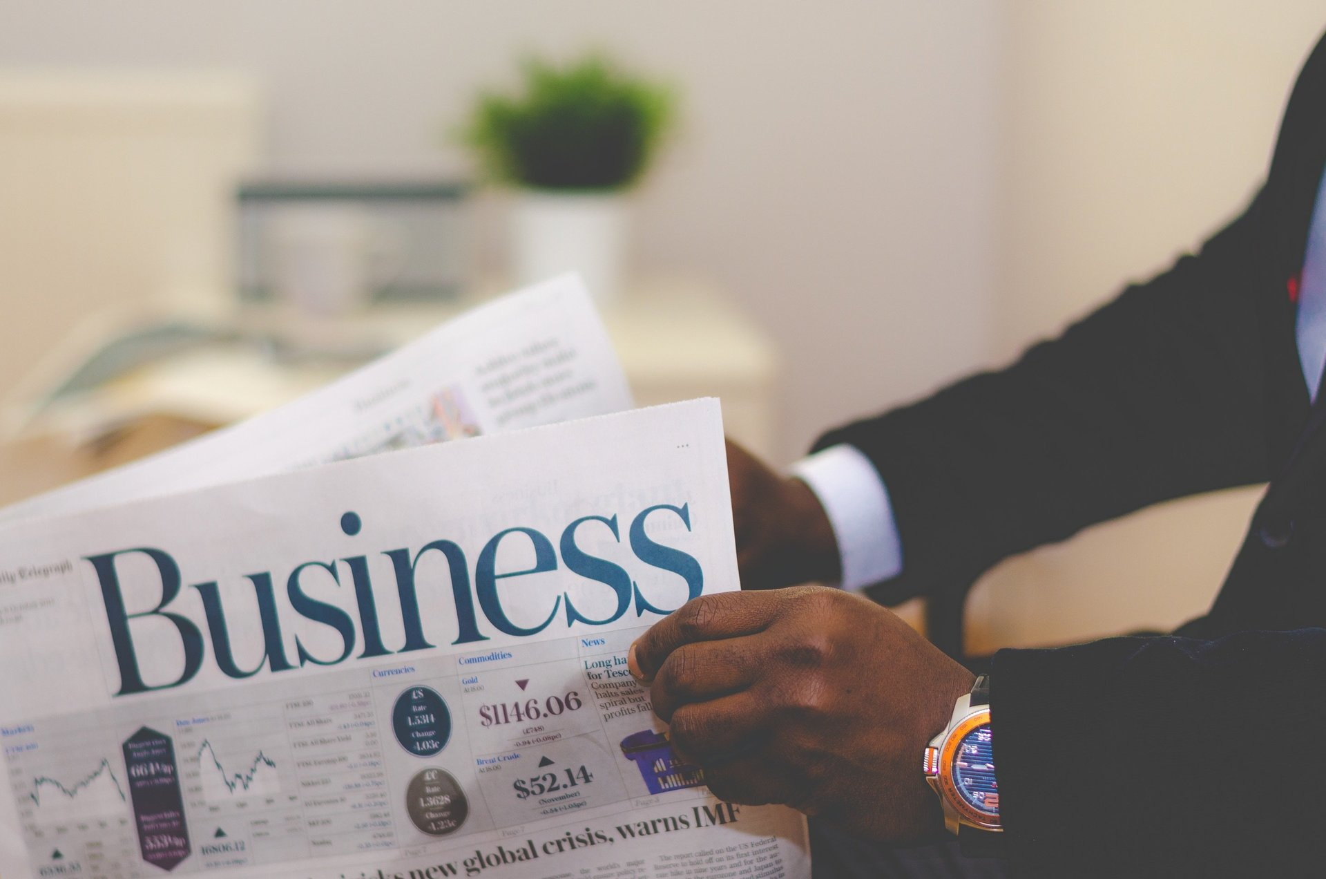 A man in a suit is reading a business newspaper.