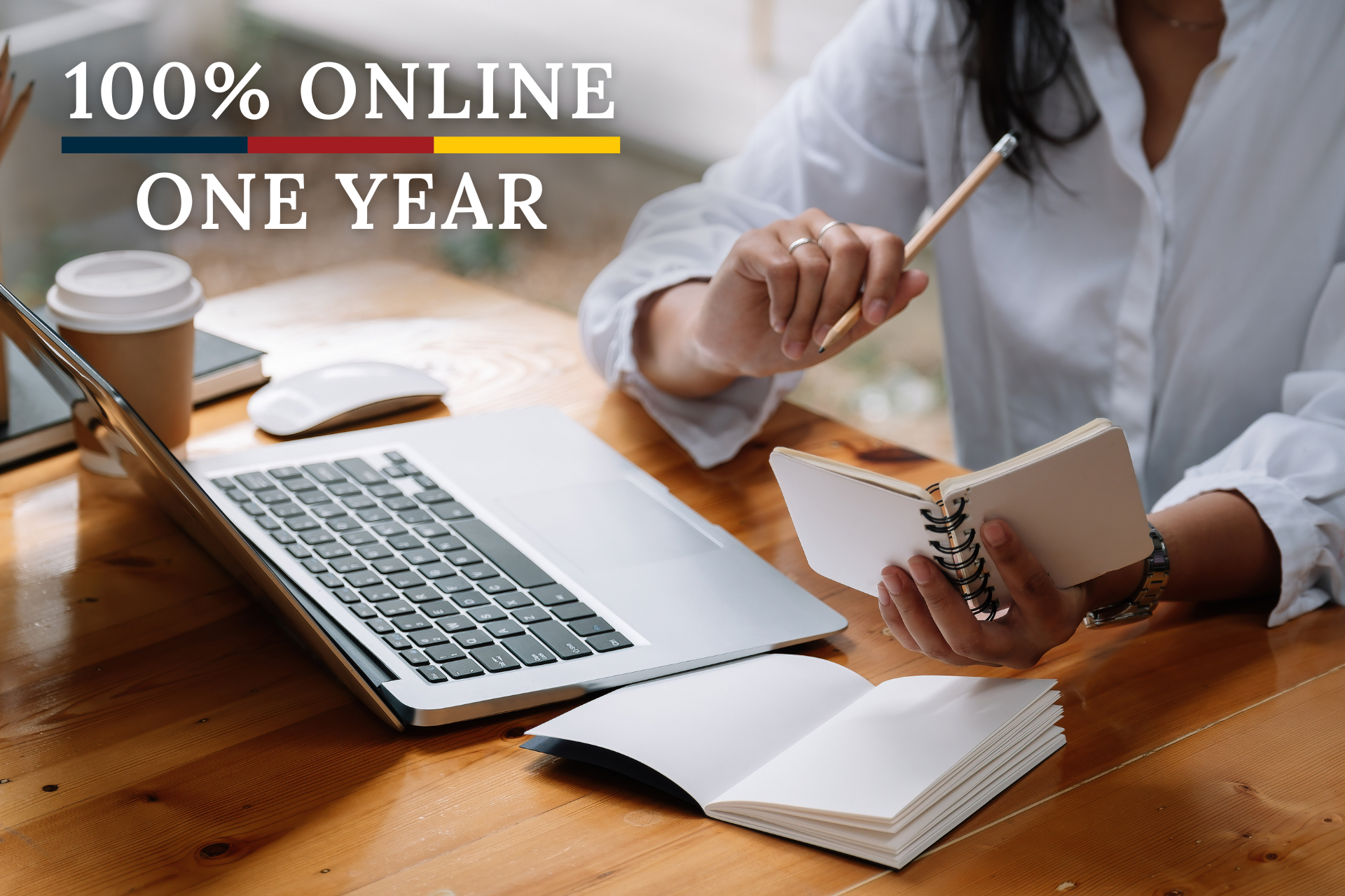 A woman is sitting at a desk with a laptop and a notebook.